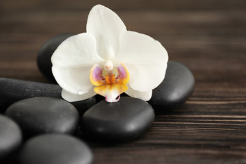 Obraz na płótnie Canvas Spa stones with beautiful orchid flower on wooden background