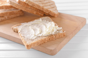 Toasted bread with cream cheese on wooden board