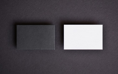 Mock up of two horizontal black and white business cards at black textured paper background. Mock-up template for branding identity.