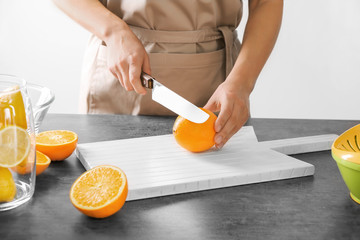 Woman cutting citrus fruit on wooden board