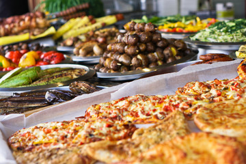 Dinner table with meat grill, roast new potatoes, vegetables, salads, sauces, snacks and lemonadeá Grilled sausage, mushrooms. Stock Photo