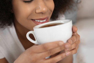Beautiful African-American woman drinking tea indoors, closeup