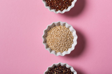 Top view of assorted Quinoa in white bowls on pink background. Flat lay with copy space. Healthy gluten free food concept.
