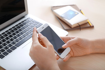 Young woman using smartphone at table