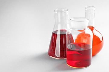 Chemical glassware with colorful liquids on light background