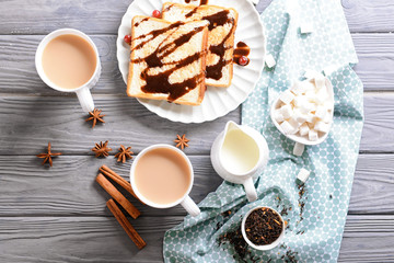 Cups of aromatic tea with milk and delicious toasts on table