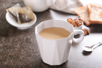 Cup of aromatic tea with milk on table