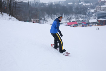 Fototapeta na wymiar Male snowboarder on slope at winter resort