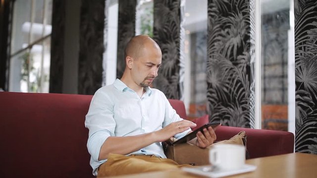 man is using tablet and drinking coffee