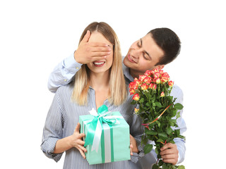 Young man giving present and flowers to his beloved girlfriend on white background