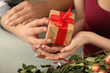 Young man giving present to his beloved girlfriend at home, closeup