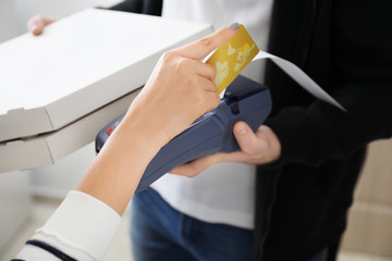 Young woman using bank terminal for credit card payment indoors. Food delivery service
