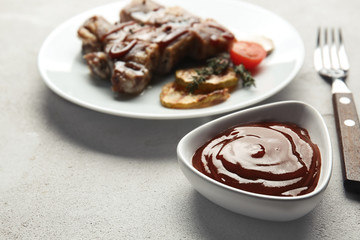 Bowl with delicious barbecue sauce on table