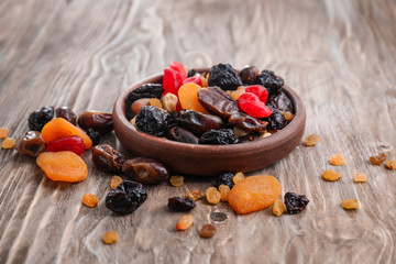 Plate with mix of dried fruits and berries on wooden background