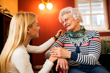 Young woman comfort her grandmother in wheelchair about her health condition