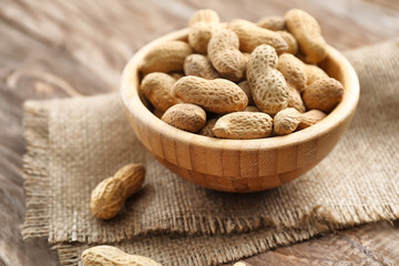 Bowl with peanuts on wooden table