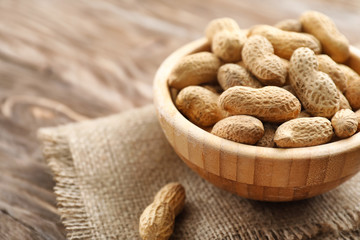 Bowl with peanuts on wooden table