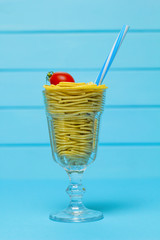 Spaghetti in a creative style. Macaroni in a glass with a straw.