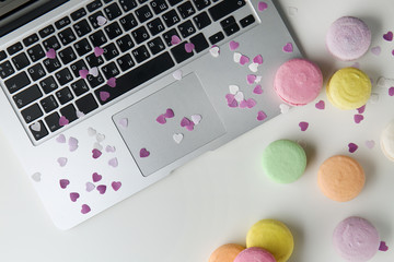 Tasty colorful macarons with laptop on white background