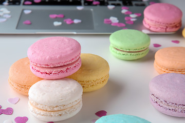 Fototapeta na wymiar Tasty colorful macarons with laptop on white background