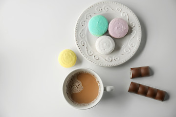 Plate with tasty colorful macarons and cup of coffee on white background