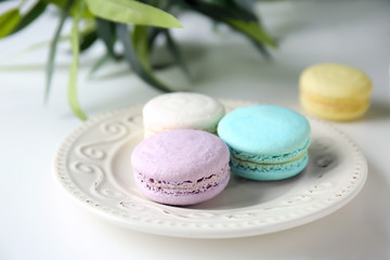 Plate with tasty colorful macarons on table