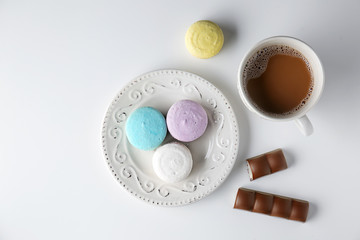 Plate with tasty colorful macarons and cup of coffee on white background