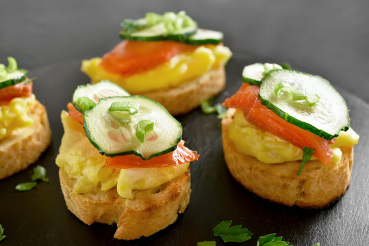 Canape with salmon, scrambled eggs and cucumber
