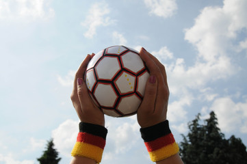 hand mit deutscher fahne hält fußball wm schweißband fanuntensil 2
