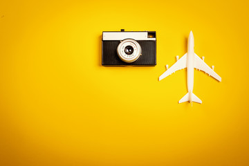 minimalistic yellow holiday background with an old camera and a toy airplane