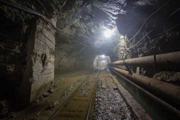 Fototapeta na wymiar Underground glod ore mine shaft tunnel gallery with railway rails