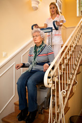 Helps senior old disabled woman to climb the stairs with  machine