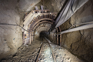 Underground glod ore mine shaft tunnel gallery with timber and light