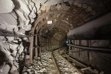 Underground glod ore mine shaft tunnel gallery with timber and light