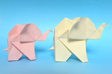 Pink and yellow origami elephant on blue background