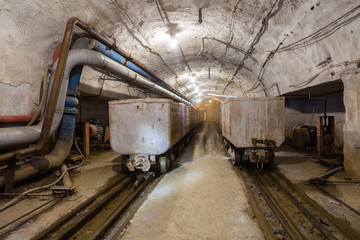Fototapeta na wymiar Underground emerald ore mine shaft tunnel gallery with light and wagons