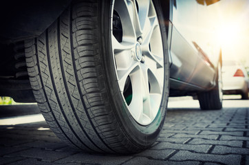 Car tire close up, parked car low angle shot - obrazy, fototapety, plakaty