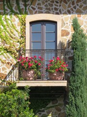 French balcony with door and pots of red Geranium flowers