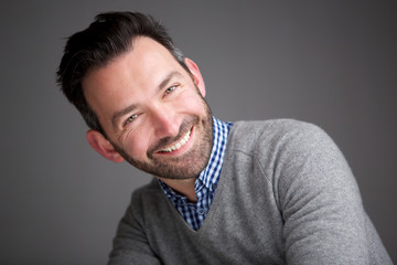 Obraz premium Close up businessman with beard smiling against gray wall