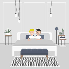 Modern bedroom interior. Couple of young adults lying in the double bed. Homosexual relationships. Gay partners. LGBTQ. Scandinavian design.
