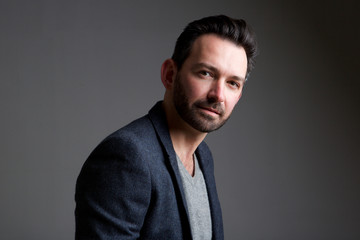 older male fashion model posing against gray background
