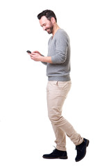 Full length side of man walking with mobile phone - obrazy, fototapety, plakaty