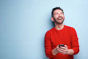 cheerful man with mobile phone looking up - Powered by Adobe