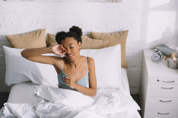 young african american woman waking up in bedroom