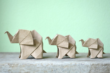 Brown origami elephant on green background