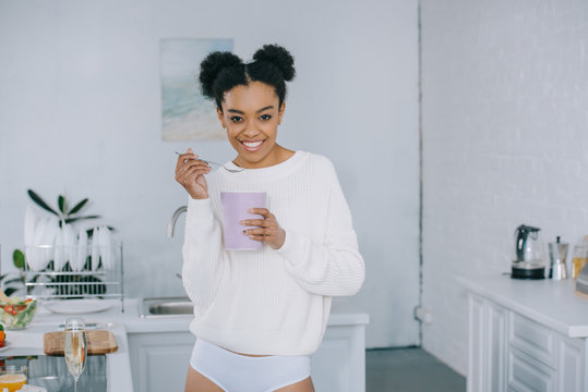 Beautiful Young Woman Eating Ice Cream From Bucket At Kitchen