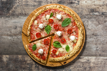 Italian pizza slice with tomatoes, cheese and basil on wooden table. Top view. 