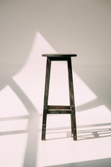 single empty tall wooden stool on white