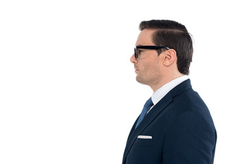 side view of businessman in suit and eyeglasses standing and looking away isolated on white
