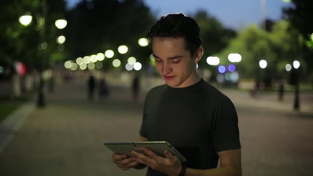 Man sms texting using app on smart phone at night in city. Handsome young business man using smartphone smiling happy. A warm summer evening.